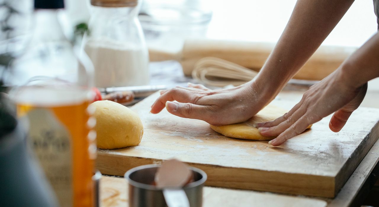 why-choose-us Female hands kneading fresh dough on wooden chopping board with flour in kitchen